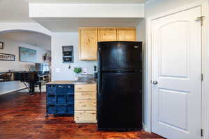 Kitchen featuring black refrigerator, light brown cabinetry, and acacia wood floor.