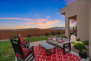 Patio terrace at dusk featuring outdoor lounge area, a mountain view, and a yard