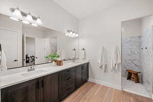 Bathroom with tiled shower, vanity, and hardwood / wood-style flooring