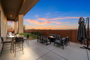 Patio terrace at dusk with an outdoor living space with a fire pit