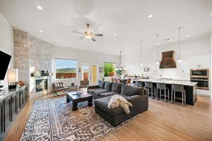 Living room featuring ceiling fan, light hardwood / wood-style floors, and a stone fireplace