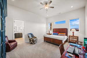 Bedroom with ceiling fan, light colored carpet, and connected bathroom