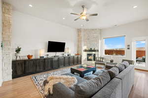 Living room featuring ceiling fan, a fireplace, and light hardwood / wood-style floors