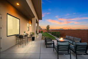 Patio terrace at dusk with an outdoor living space with a fire pit