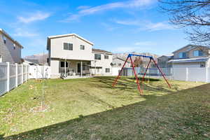 Rear view of house featuring a trampoline, a playground, a patio, and a yard