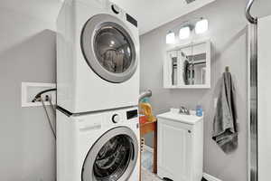 Washroom featuring sink and stacked washer and clothes dryer