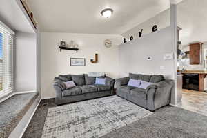 Carpeted living room with lofted ceiling