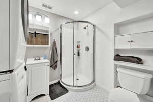 Bathroom with vanity, toilet, and a shower with door