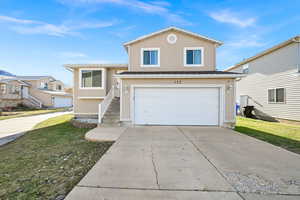 View of property featuring a garage and a front lawn