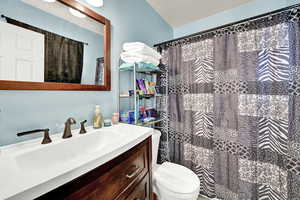 Bathroom featuring a shower with curtain, vanity, and toilet