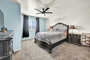 Carpeted bedroom with ceiling fan and a textured ceiling