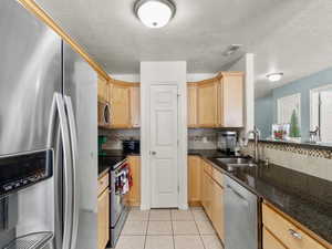 Kitchen featuring decorative tile backsplash, appliances with stainless steel finishes, granite counters with under counter stainless steel sink