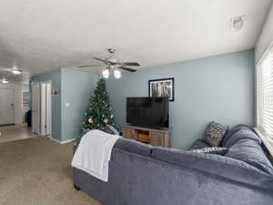 Living room featuring light carpet, a ceiling fan, and a half bath on the main floor