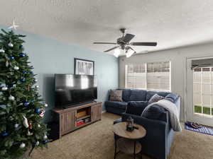 Carpeted living room with ceiling fan, open and bright feeling