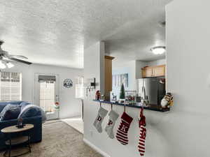 Interior space with light carpet, stainless steel refrigerator with ice dispenser, ceiling fan, and kitchen peninsula