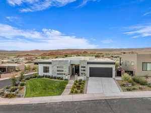 View of front of house with a mountain view, a garage, and a front lawn