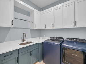 Laundry area with cabinets, separate washer and dryer, and sink