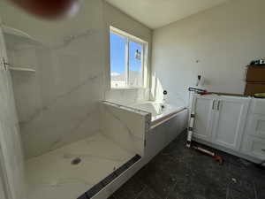 Bathroom featuring a garden tub and a marble finish shower