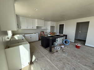 Kitchen featuring baseboards, a textured ceiling, recessed lighting, and white cabinets