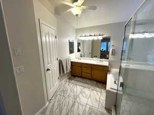 Bathroom featuring vanity, lofted ceiling, a shower with door, ceiling fan, and a textured ceiling