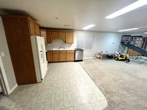 Kitchen featuring dishwasher, sink, light colored carpet, and white refrigerator with ice dispenser