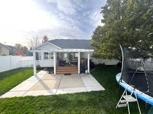 Back of house with a yard, a trampoline, a patio area, and a wooden deck