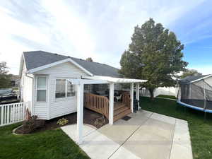 Exterior space with a lawn, a deck, a trampoline, and a patio