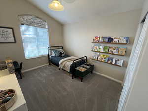 Bedroom with dark colored carpet and lofted ceiling