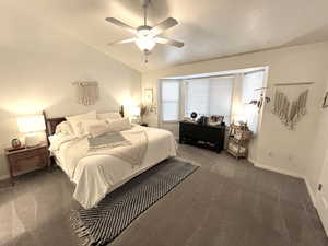 Carpeted bedroom with ceiling fan and vaulted ceiling