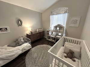 Bedroom with dark wood-type flooring and lofted ceiling