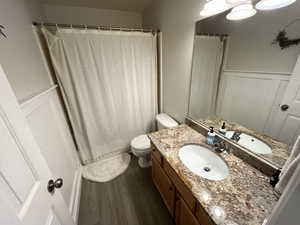 Bathroom featuring toilet, hardwood / wood-style floors, vanity, and a shower with curtain