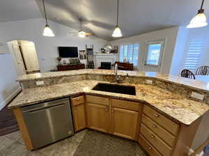 Kitchen with ceiling fan, sink, stainless steel dishwasher, decorative light fixtures, and vaulted ceiling