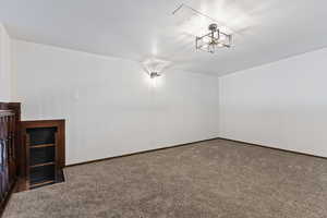 Spare room featuring a chandelier and carpet floors