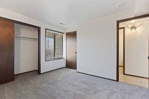 Unfurnished bedroom featuring a closet and light colored carpet