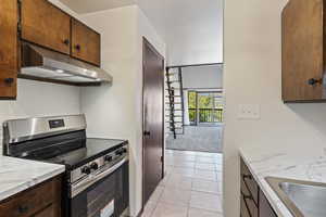 Kitchen with light tile patterned flooring, sink, and gas range