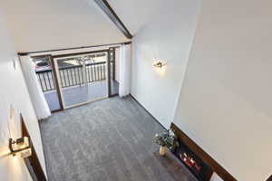 Spare room featuring a fireplace, beamed ceiling, carpet, and high vaulted ceiling