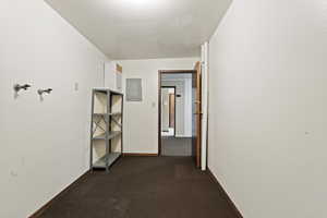 Hall featuring dark colored carpet and electric panel