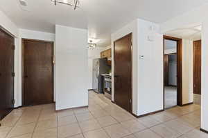 Kitchen with an inviting chandelier, light tile patterned flooring, and appliances with stainless steel finishes