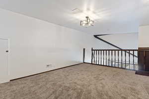 Empty room featuring carpet and an inviting chandelier