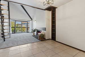 Unfurnished living room with light tile patterned flooring, high vaulted ceiling, and an inviting chandelier