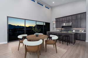 Dining space with a towering ceiling, sink, and light hardwood / wood-style flooring