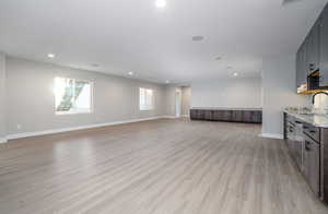 Unfurnished living room featuring sink and light hardwood / wood-style flooring