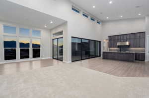 Unfurnished living room with a towering ceiling and light hardwood / wood-style floors