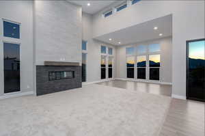 Living room featuring a fireplace, a towering ceiling, and light hardwood / wood-style flooring