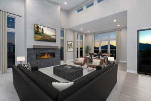 Living room with light wood-type flooring, a fireplace, and a high ceiling