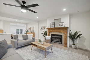 Living room featuring ceiling fan, a fireplace, and light tile patterned floors