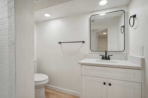 Bathroom featuring hardwood / wood-style flooring, vanity, and toilet