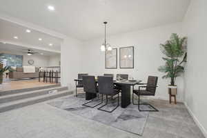 Dining room with carpet floors and ceiling fan with notable chandelier