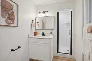 Bathroom featuring a shower with shower door, wood-type flooring, and vanity