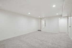 Basement with light carpet and a textured ceiling